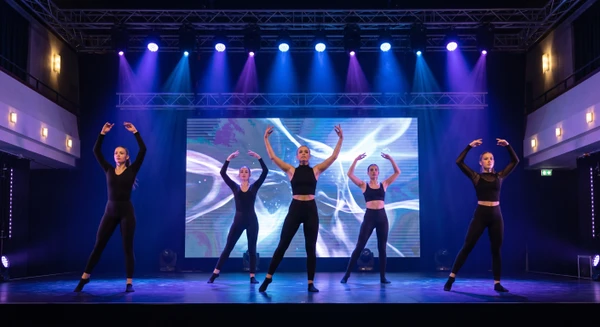 Groupe de danseuses professionnelles en tenue noire coordonnée exécutant une chorégraphie contemporaine dynamique sur scène, éclairées par des projecteurs scéniques gérant des jeux de lumière colorés (principalement bleus et violets). Fond LED haute résolution affichant un décor artistique sophistiqué. Composition en formation synchronisée, bras levés expressifs, éclairage dramatique théâtral, prise de vue frontale en plan américain, photographie professionnelle haute résolution capturant l'énergie et la synchronisation de la performance.